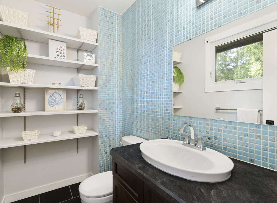 This modern bathroom features a stylish blue tiled accent wall and a sleek vanity with an undermount sink.