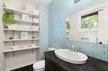 This modern bathroom features a stylish blue tiled accent wall and a sleek vanity with an undermount sink.