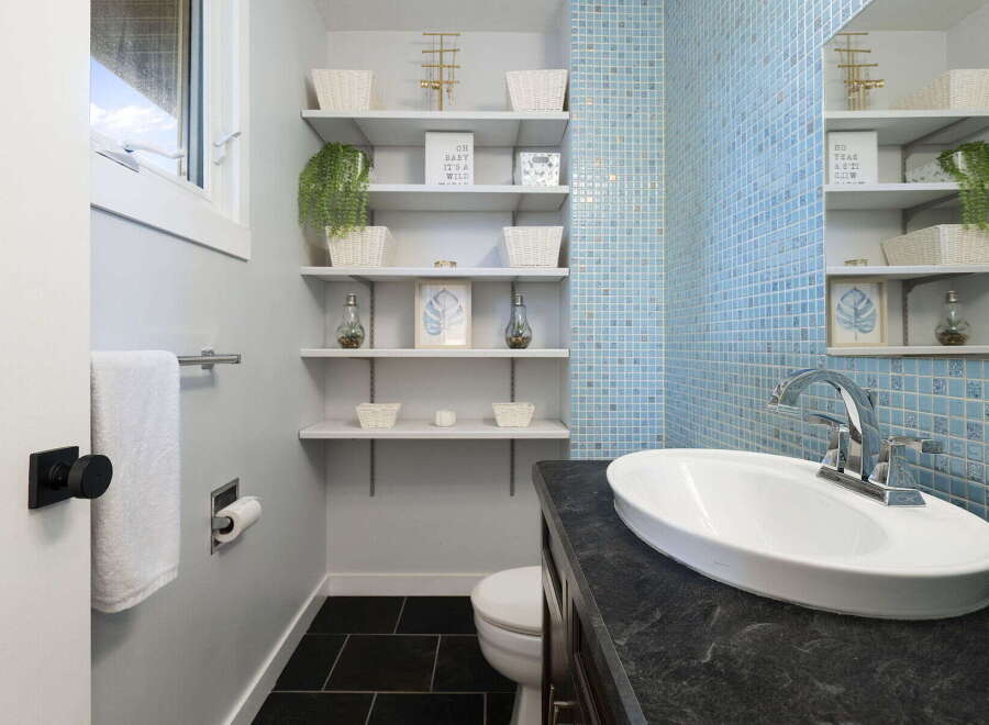 This stylish bathroom features a sleek vanity with a dark stone countertop and a modern vessel sink, complemented by a chrome faucet.