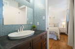 This charming bathroom features a sleek vanity with a modern faucet and a vessel sink, complemented by a striking blue mosaic tile backsplash.