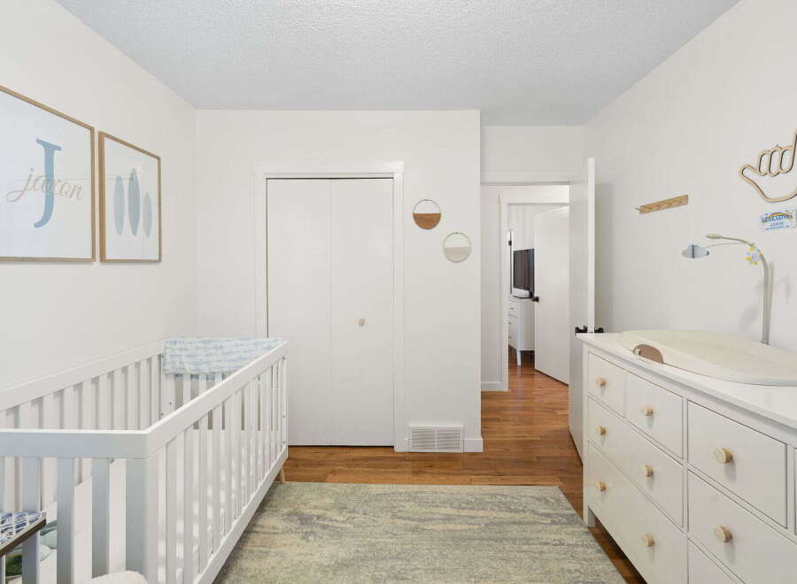 This charming nursery features a white crib and a matching dresser with a changing pad, perfect for a new arrival.