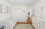 This charming nursery features a white crib and a matching dresser with a changing pad, perfect for a new arrival.