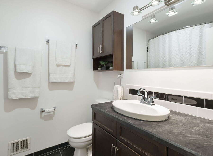 This bathroom features a modern vanity with a dark countertop and a sleek faucet, complemented by a white oval sink.