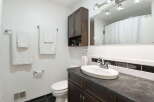 This bathroom features a modern vanity with a dark countertop and a sleek faucet, complemented by a white oval sink.