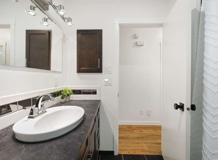 This modern bathroom features a sleek vanity with a dark countertop and a white undermount sink, complemented by a chrome faucet.