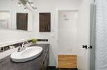 This modern bathroom features a sleek vanity with a dark countertop and a white undermount sink, complemented by a chrome faucet.