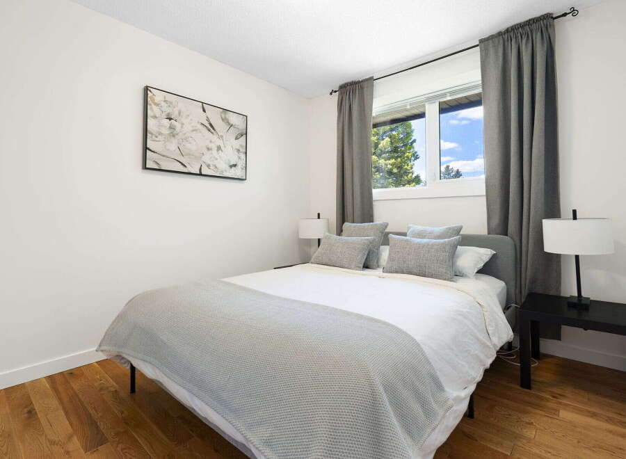 This inviting bedroom features a comfortable queen-size bed adorned with plush grey pillows and a soft, textured throw blanket.