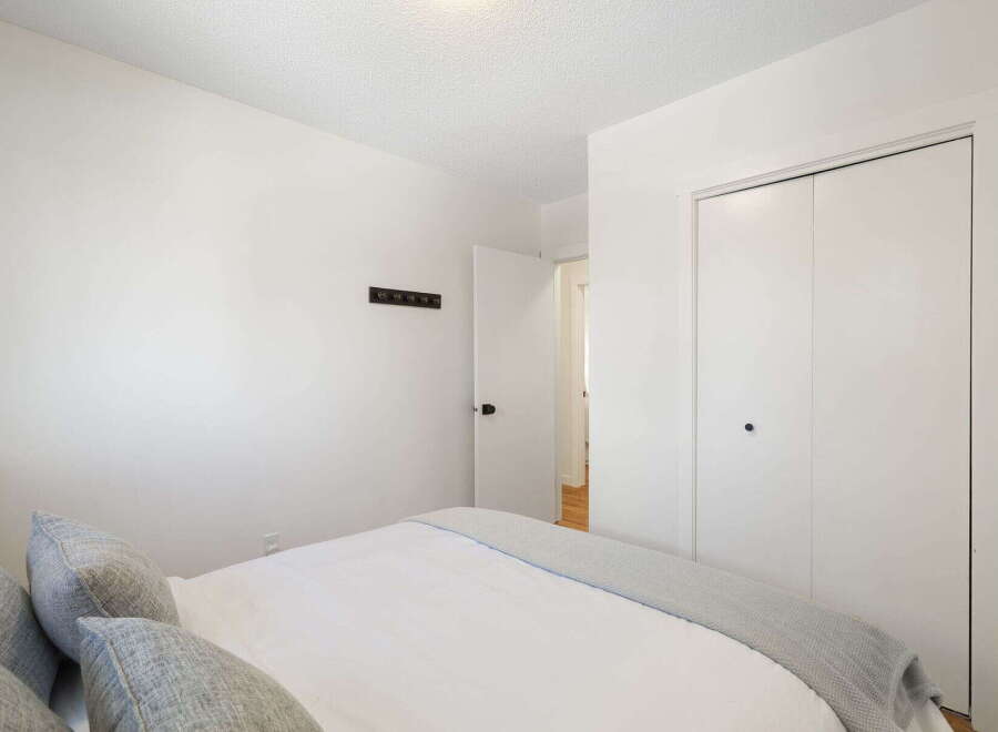 This bedroom features a comfortable bed with plush pillows and a cozy grey throw blanket, perfect for relaxation.