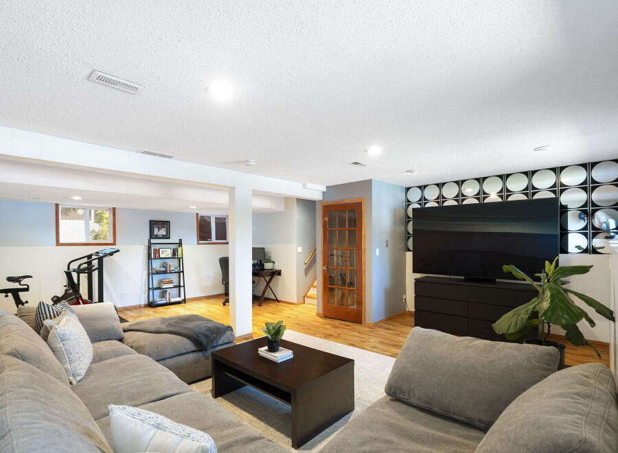 This finished basement offers a versatile living space with a large sectional sofa perfect for movie nights.