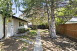 Step into this charming backyard, featuring a welcoming pathway leading through lush greenery and mature trees.