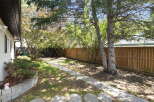 Enjoy the outdoors in this charming backyard featuring a paved walkway leading through lush greenery.