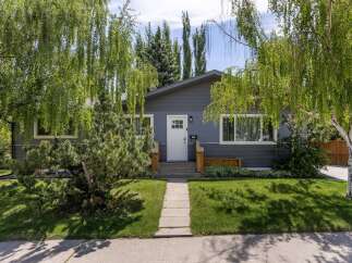 Charming bungalow with a freshly painted dark gray exterior and a welcoming white front door.