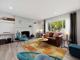 Step into this inviting living room, featuring a cozy brick fireplace and a large window offering a view of the lush outdoors.