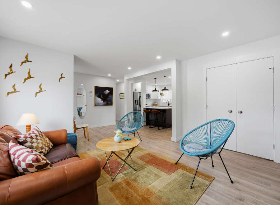 Experience modern living in this beautifully appointed open-concept space, featuring a stylish living area with a comfortable leather sofa and vibrant accent pillows.