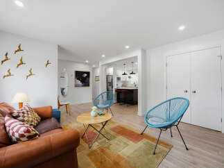 Experience modern living in this beautifully appointed open-concept space, featuring a stylish living area with a comfortable leather sofa and vibrant accent pillows.