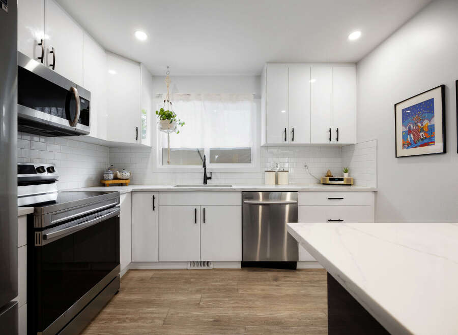 Discover this stunning modern kitchen, featuring sleek white cabinetry, a subway tile backsplash, and stainless steel appliances.