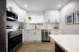 Discover this stunning modern kitchen, featuring sleek white cabinetry, a subway tile backsplash, and stainless steel appliances.