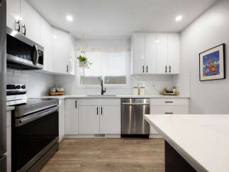 Discover this stunning modern kitchen, featuring sleek white cabinetry, a subway tile backsplash, and stainless steel appliances.