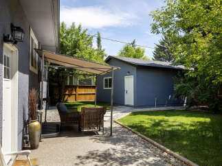 Enjoy outdoor living in this charming backyard featuring a spacious patio area with comfortable seating and a shaded canopy.