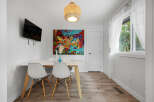 Bright and modern dining area featuring a sleek white table with minimalist chairs, perfect for intimate gatherings.