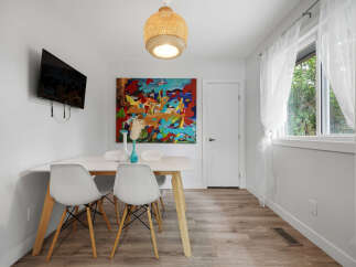 Bright and modern dining area featuring a sleek white table with minimalist chairs, perfect for intimate gatherings.