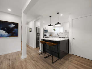 Experience modern living in this stunning kitchen and dining area, featuring sleek white cabinetry, a stylish island with bar seating, and elegant pendant lighting.