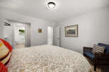 This inviting bedroom features a comfortable bed with a decorative duvet and a cozy armchair with accent pillows.