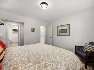 This inviting bedroom features a comfortable bed with a decorative duvet and a cozy armchair with accent pillows.