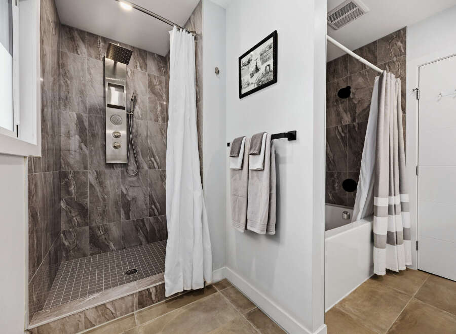 Experience modern luxury in this stunning bathroom featuring a sleek shower system with multiple jets and a rainfall showerhead.