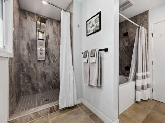 Experience modern luxury in this stunning bathroom featuring a sleek shower system with multiple jets and a rainfall showerhead.