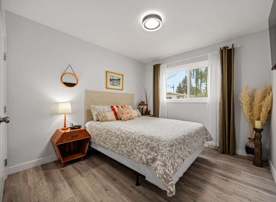 This inviting bedroom features a comfortable queen-size bed with a patterned duvet and decorative pillows, complemented by a textured headboard.