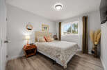 This inviting bedroom features a comfortable queen-size bed with a patterned duvet and decorative pillows, complemented by a textured headboard.