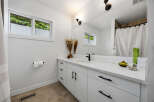 This modern bathroom features a sleek white vanity with black hardware, complemented by a white quartz countertop and subway tile backsplash.