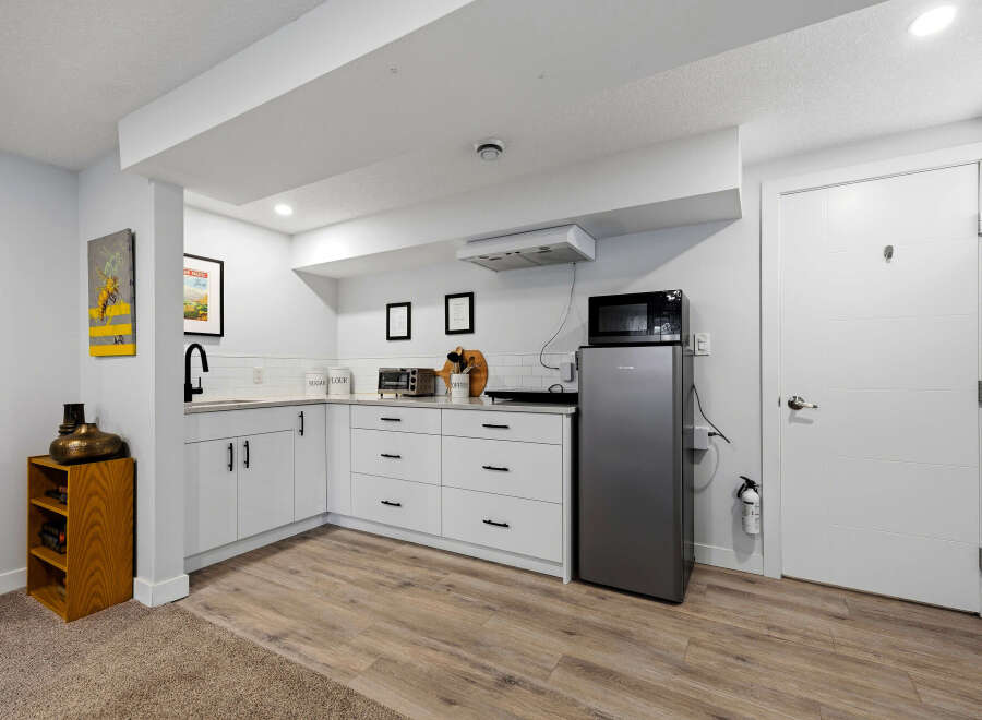 Discover this charming basement suite featuring a modern kitchenette equipped with a microwave, refrigerator, and ample cabinet space.