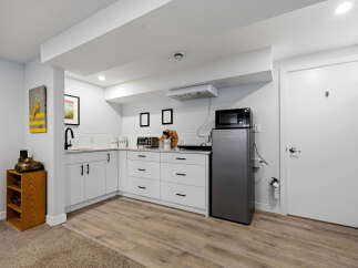 Discover this charming basement suite featuring a modern kitchenette equipped with a microwave, refrigerator, and ample cabinet space.