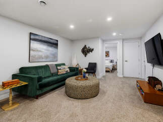 Experience modern comfort in this stylish living room, featuring a plush emerald green sofa perfect for relaxation.