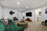 Step into this inviting living space featuring a plush green sofa complemented by a decorative ottoman and a modern wall-mounted TV.