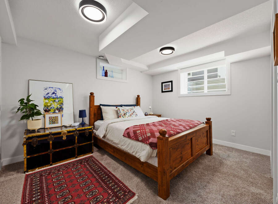 This charming bedroom features a cozy wooden bed with a red and white patterned blanket, complemented by a vintage-style trunk serving as a nightstand.