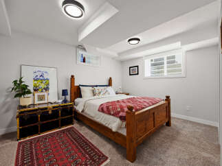 This charming bedroom features a cozy wooden bed with a red and white patterned blanket, complemented by a vintage-style trunk serving as a nightstand.