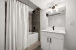 This modern bathroom features a sleek white vanity with a marble countertop and a black faucet, complemented by a subway tile backsplash.