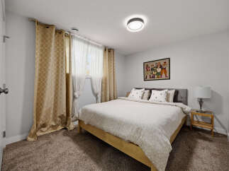 Discover comfort and style in this inviting bedroom, featuring a plush carpeted floor and elegant gold patterned curtains that add a touch of warmth.