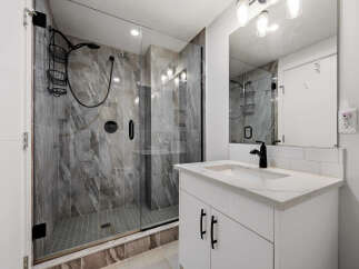 Experience modern luxury in this stunning bathroom, featuring a spacious walk-in shower with elegant marble-look tiles and a sleek black shower system.