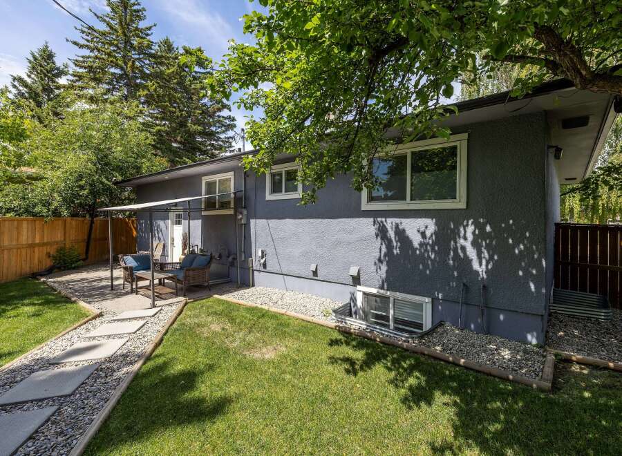Enjoy outdoor living in this charming backyard featuring a paved patio area with comfortable seating, perfect for entertaining guests.