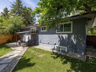 Enjoy outdoor living in this charming backyard featuring a paved patio area with comfortable seating, perfect for entertaining guests.