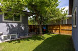 Enjoy outdoor living in this charming backyard featuring a lush green lawn and a mature tree perfect for shade.