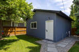 Discover this charming property featuring a detached garage with a modern blue stucco exterior and a white door.