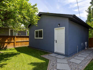 Discover this charming property featuring a detached garage with a modern blue stucco exterior and a white door.
