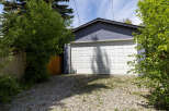 This image showcases a detached garage with a classic white overhead door, set against a textured blue exterior wall.