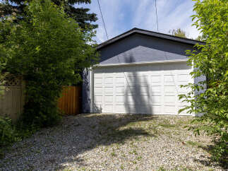 This image showcases a detached garage with a classic white overhead door, set against a textured blue exterior wall.