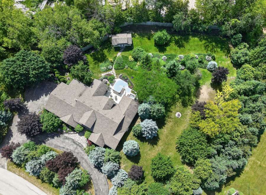 Discover this stunning property featuring a spacious home with a multi-faceted roof, surrounded by lush greenery and mature trees.